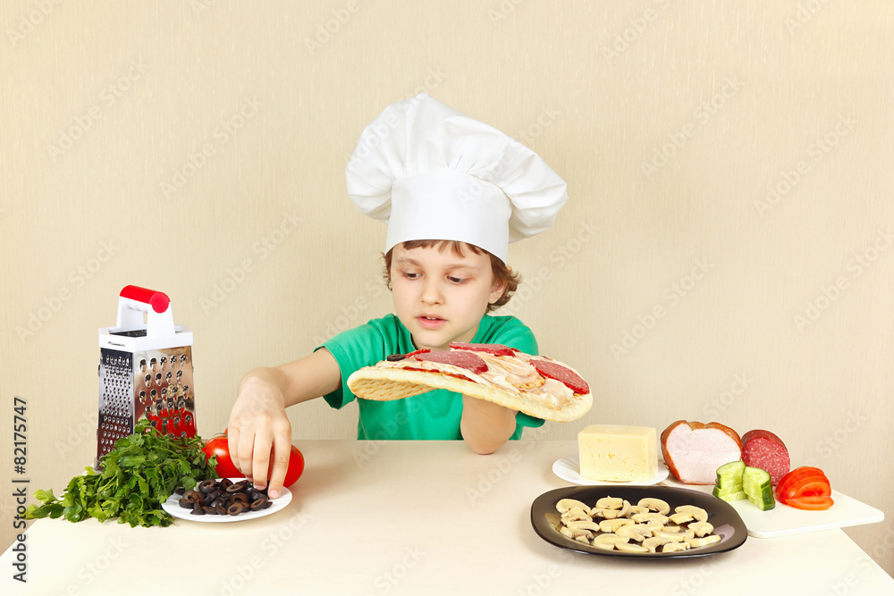 Young chef puts olives on the pizza crust Young chef puts olives on the pizza crust