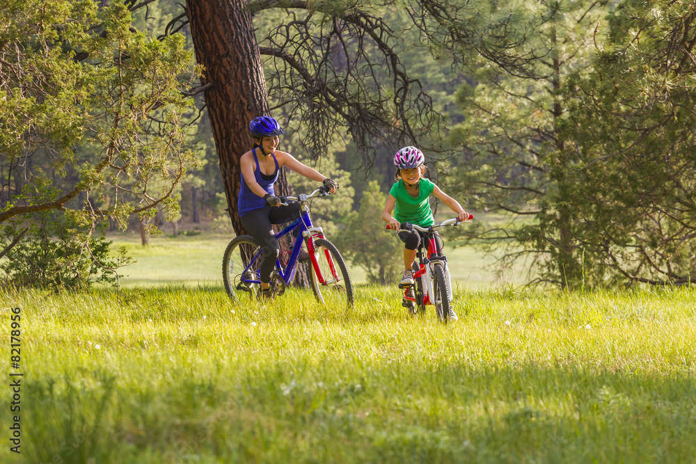 Mother and daughter riding mountain bikes in meadow Mother and daughter riding mountain bikes in meadow
