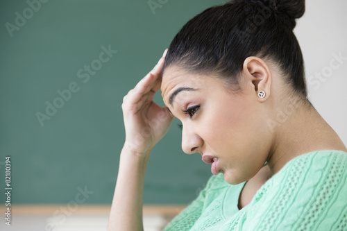 Hispanic woman rubbing forehead