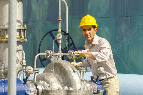 Hispanic worker checking valves photo