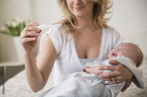 Caucasian mother taking crying baby's temperature photo