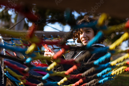 Young girl texting/using phone while sitting on hammock