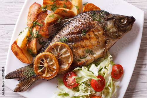 Canvas Print grilled fish with fried potatoes and salad horizontal top view