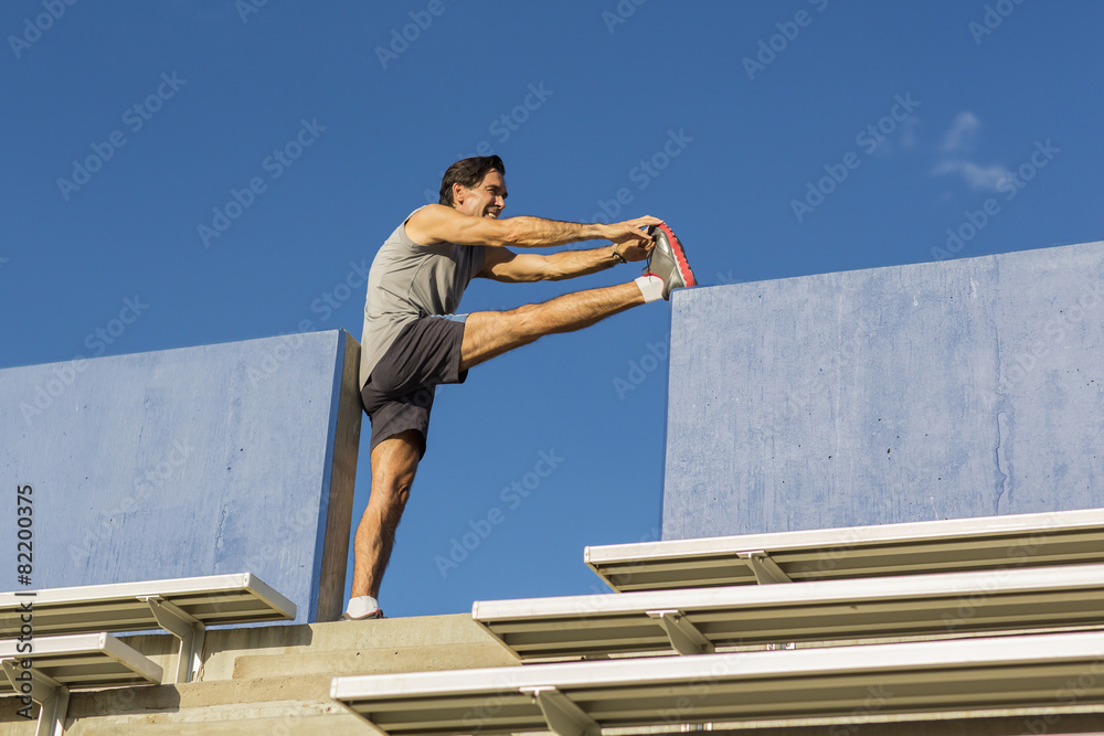 Hispanic athlete stretching on bleachers Hispanic athlete stretching on bleachers