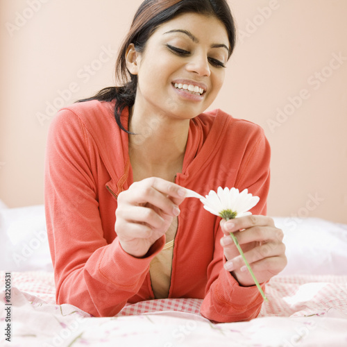 Mixed Race woman pulling petals off flower photo