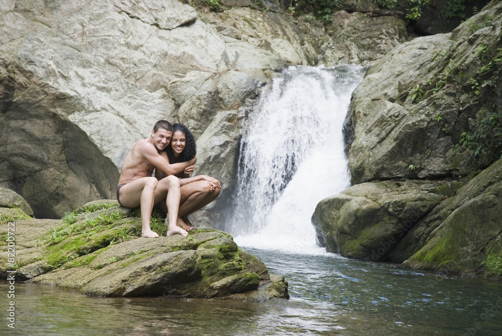 Couple swimming in pool near waterfall Couple swimming in pool near waterfall