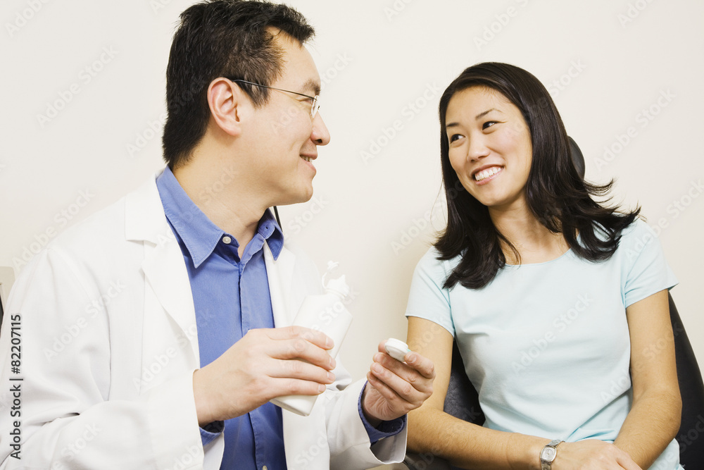 Asian male optometrist giving contact lenses to patient Asian male optometrist giving contact lenses to patient