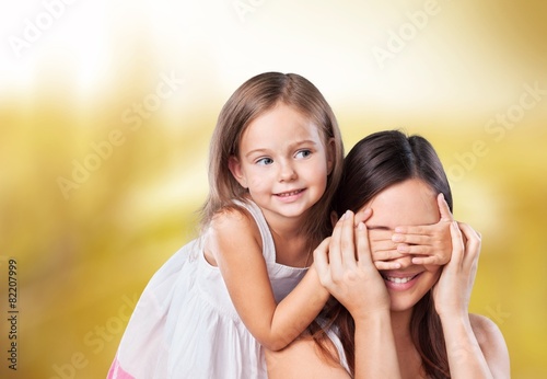 Background. Young daughter closes hands eyes mom - isolated