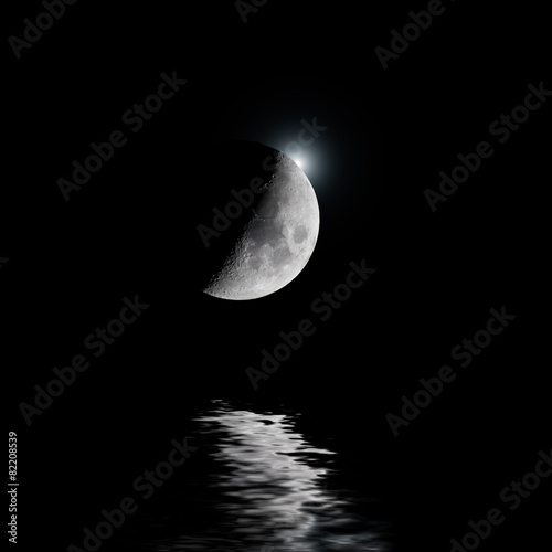 Backlit moon with white star over water