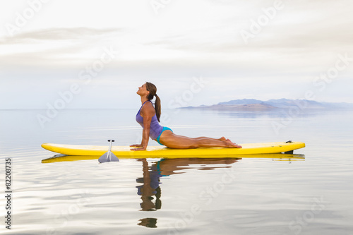 Filipino woman practicing yoga on paddle board