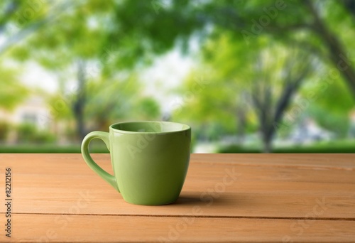 Backdrop. Green mug on wooden table over grunge background