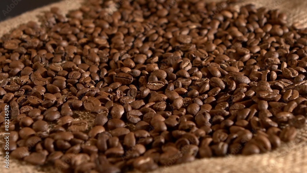 Coffee beans and falling on burlap sacking background, rotation