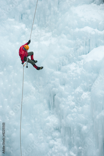 Caucasian man rappelling down ice wall