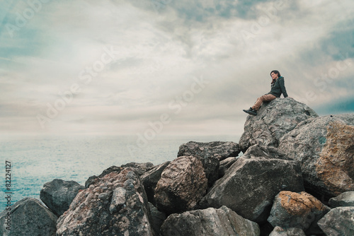 Woman sitting on stone near the sea