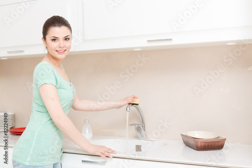 Woman cleaning tap in kitchen