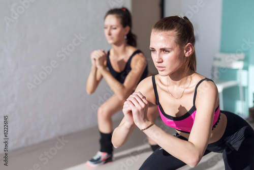 two girls doing squats together indoors training warm up at gym © undrey