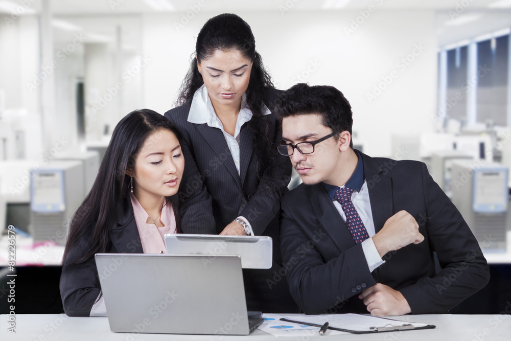 Businesswoman showing tablet at her partners Businesswoman showing tablet at her partners