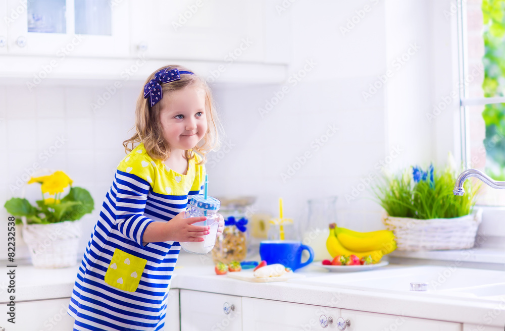Little girl preparing breakfast in a white kitchen - obrazy, fototapety, plakaty 