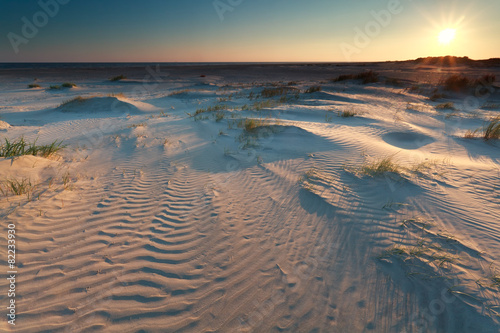 sunrise over sand dunes on coast