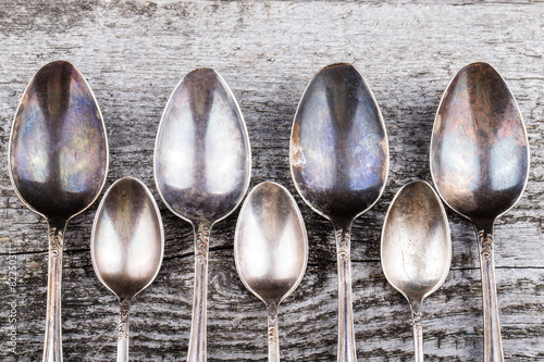 Obraz na płótnie Antic metal spoons on old wooden board. Selective focus
