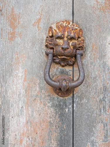 Rusty old iron door knocker on door. Lion.
