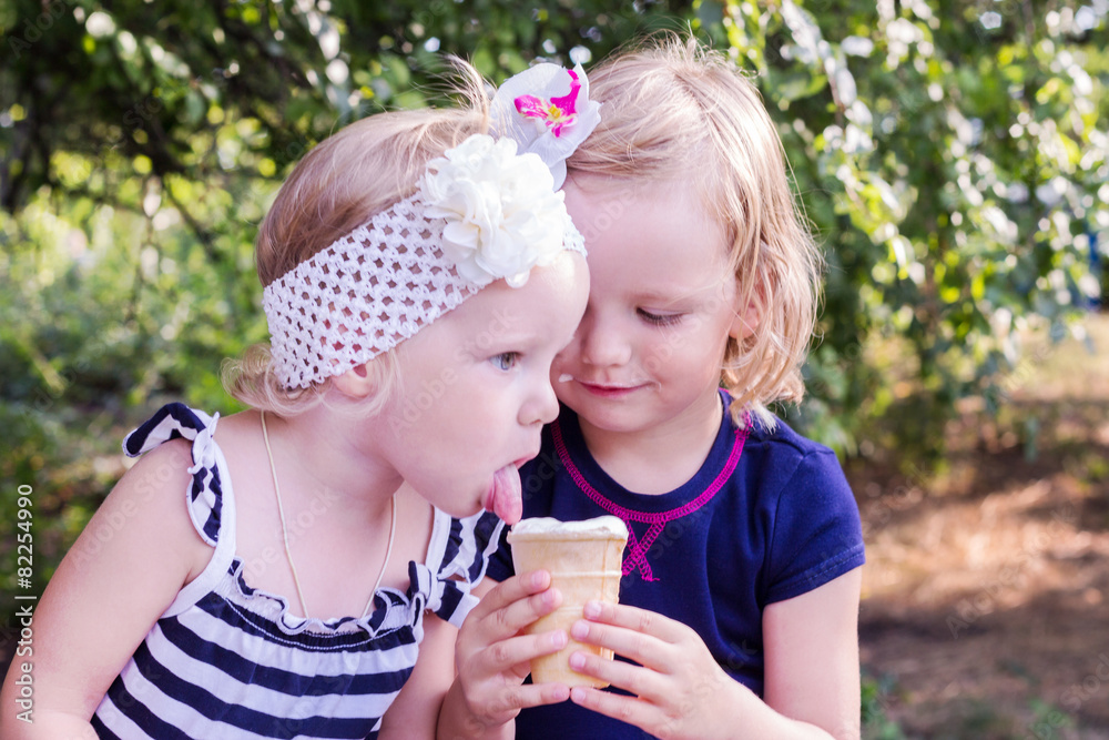 Pretty little girls (sisters) eating ice cream in the summer the Pretty little girls (sisters) eating ice cream in the summer the
