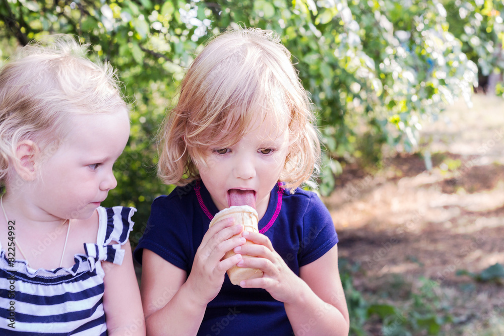 Pretty little girls (sisters) eating ice cream in the summer the Pretty little girls (sisters) eating ice cream in the summer the