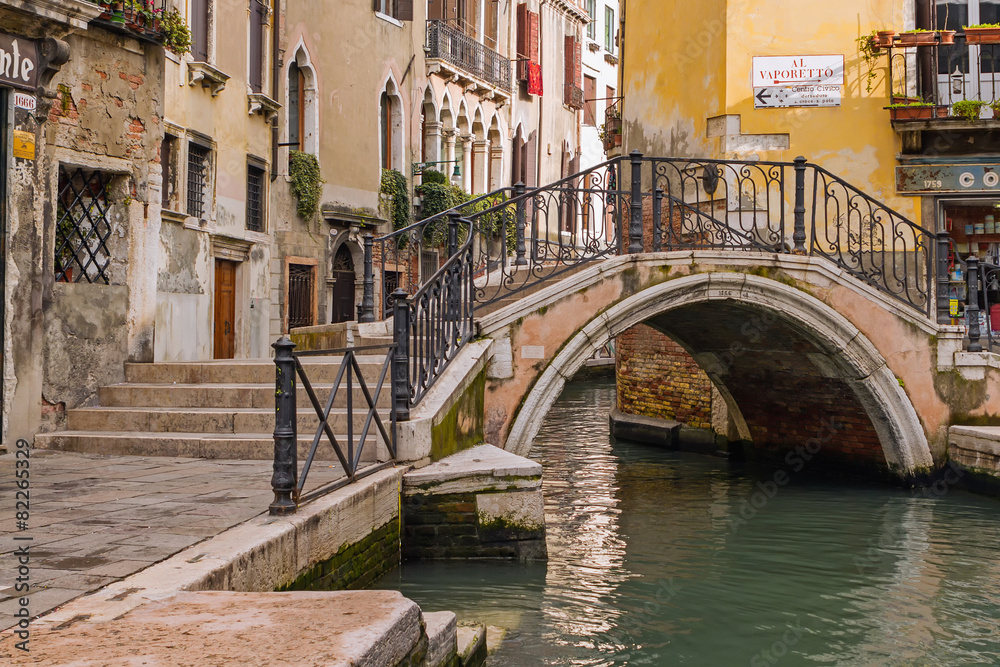 Arch bridge over a narrow canal in Venice, Italy.