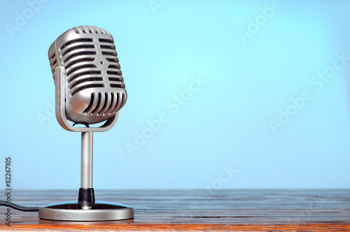 Vintage microphone on the table with cyanic background