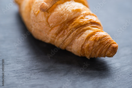 Tasty french croissant on a black stone plate