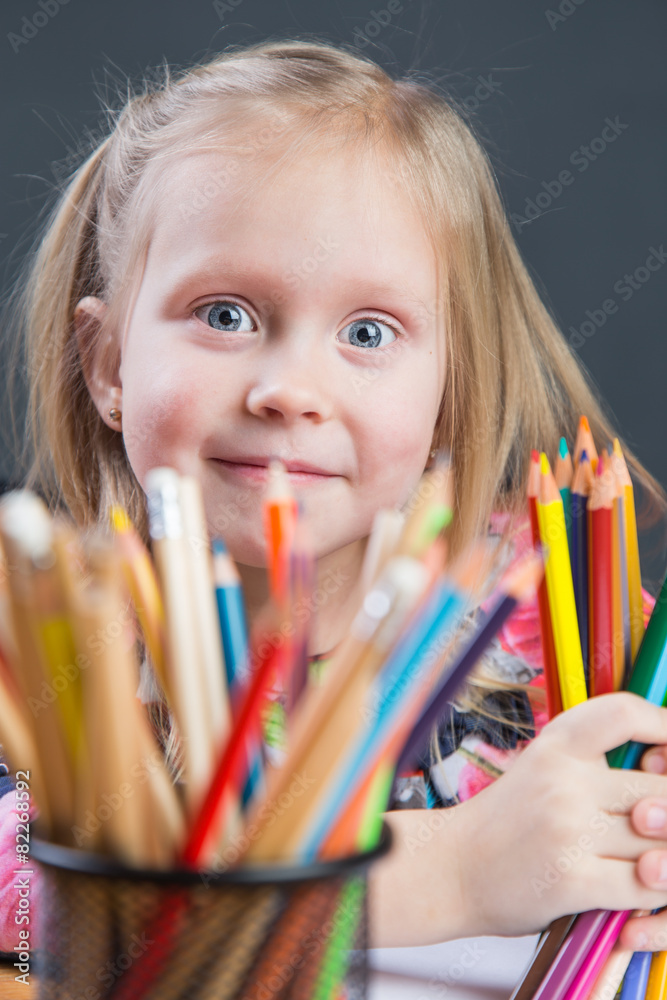 Small young girl drawing pictures with color pencils