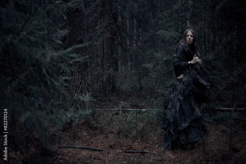 man with long hair in the dark forest