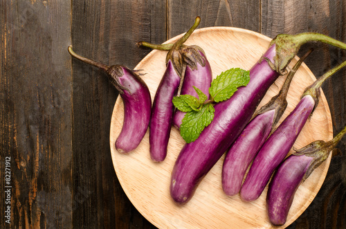 Raw eggplants on wooden plate