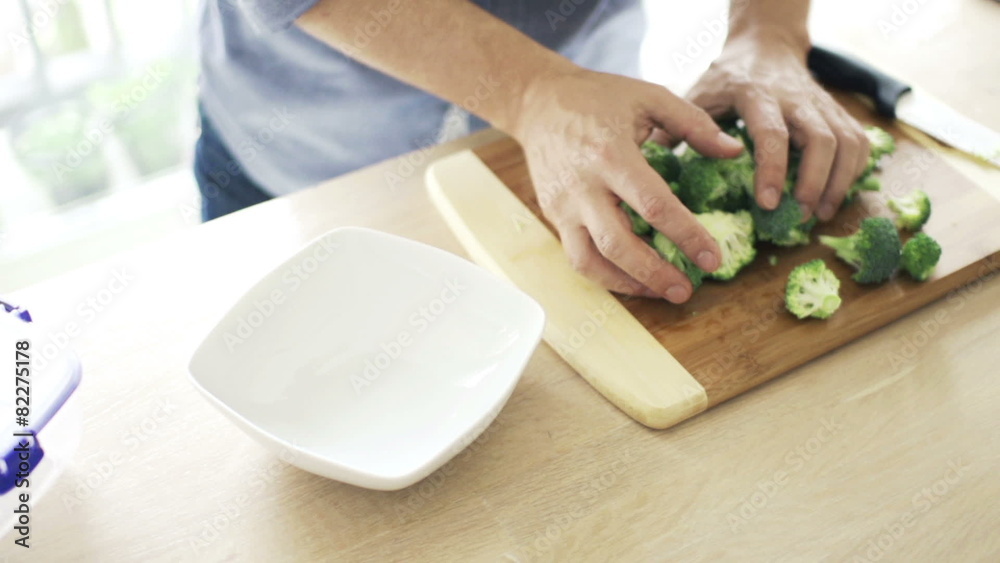 Man putting broccoli into bowl in kitchen
Man putting broccoli into bowl in kitchen