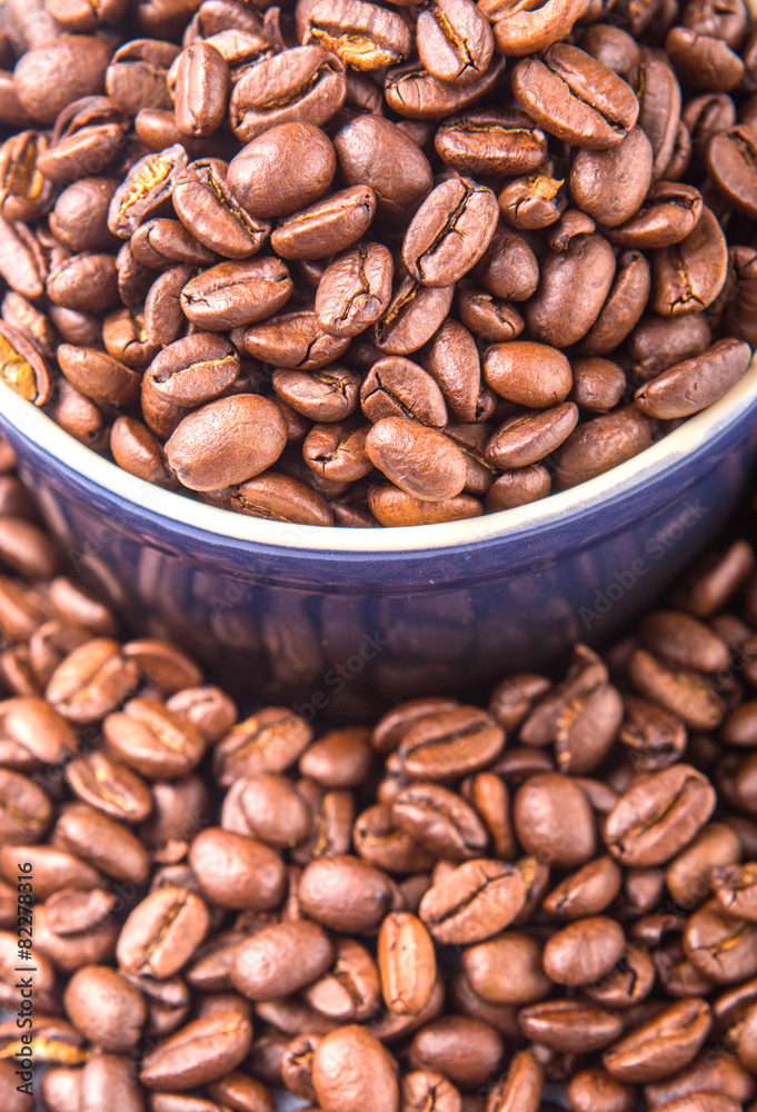 Fototapeta premium Roasted coffee beans in a blue ceramic pot over white background