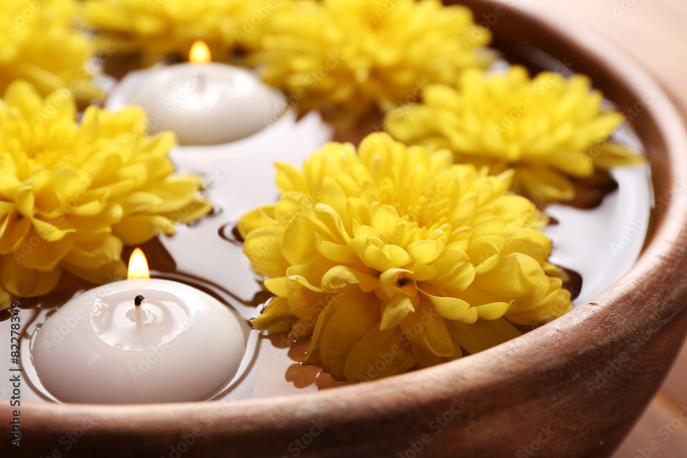 Bowl of spa water with flowers and candles, closeup