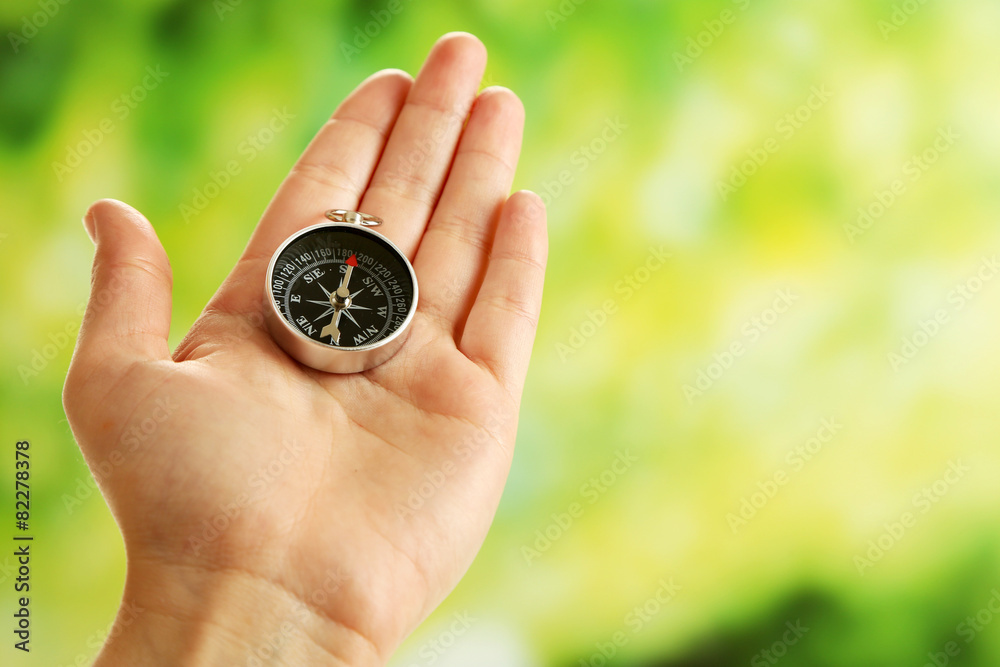 Female hand with compass on bright blurred background Female hand with compass on bright blurred background
