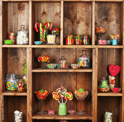 Colorful candies in jars on wooden shelves  close-up