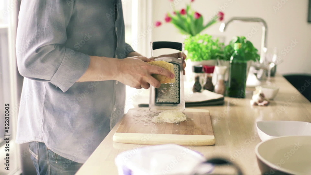 Man grating cheese on grater in kitchen
Man grating cheese on grater in kitchen