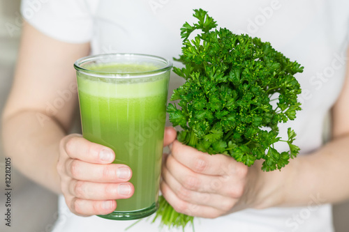 A glass of apple juice and celery bunch parsley
