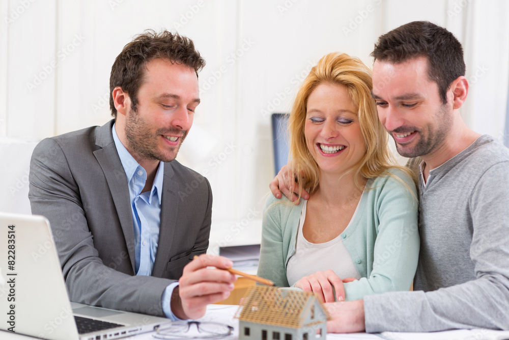 Fototapeta premium Real estate agent present project on miniature house to a young