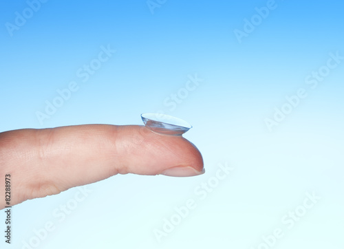 contact lens on finger on blue background