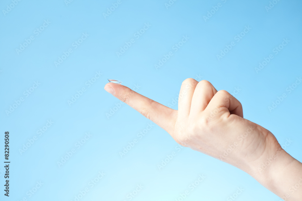 contact lens on finger, blue background contact lens on finger, blue background