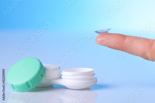 contact lens on finger and a case on blue background