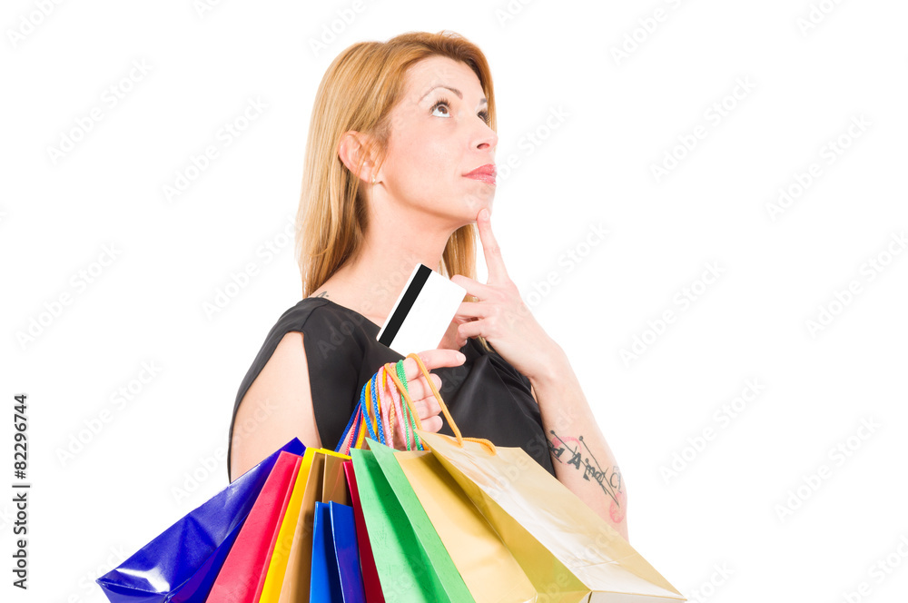Shopping woman holding credit or debit card and thinking Shopping woman holding credit or debit card and thinking