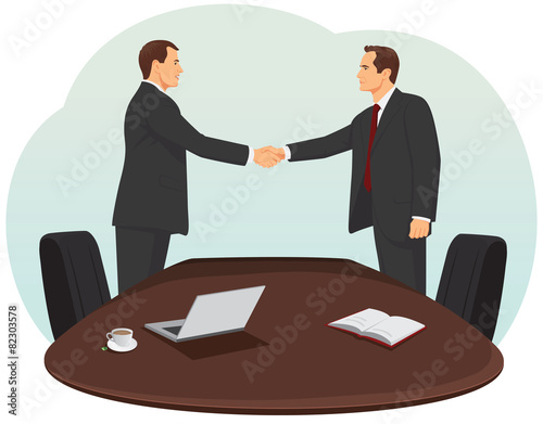 Two businessmen in suits are handshaking in the office