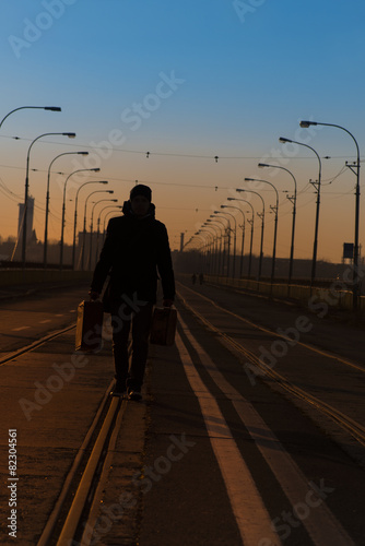 silhouette man with suitcase on a bridge © tutye