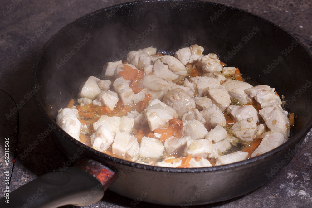 Grilled meat with vegetables in a pan on a hot plate during coo Grilled meat with vegetables in a pan on a hot plate during coo