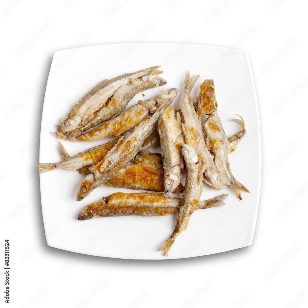 Pile of fried smelts fish lays on a white plate, top view isolat Pile of fried smelts fish lays on a white plate, top view isolat