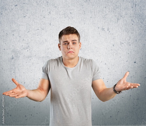 Question. Closeup portrait of dumb clueless young man, arms out photo